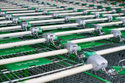 Row of parked trolleys in supermarket. many empty green shopping carts in row.