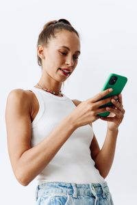 Young woman using mobile phone against white background