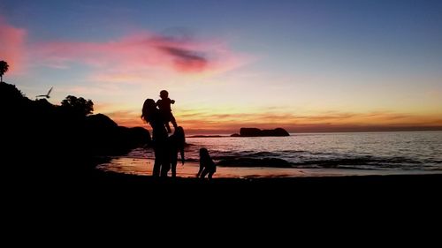 Silhouette of people on beach at sunset