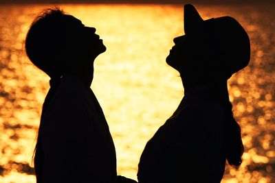 Side view of silhouette couple standing during sunset
