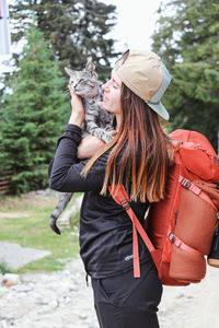 Side view of woman holding cat standing outdoors