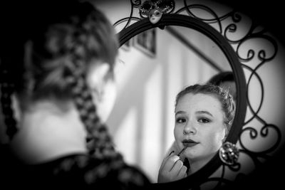 Portrait of young girl looking through mirror