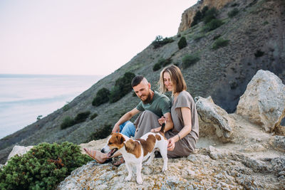 Happy couple with favourite pet. young man and woman have walk near sea.