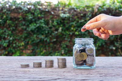 Close-up of a hand holding jar against wooden table