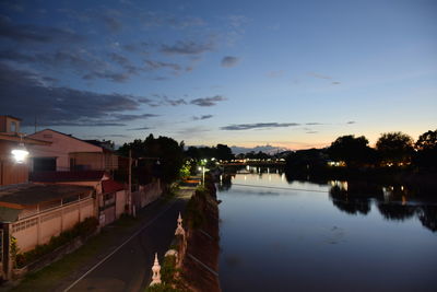 Scenic view of lake by buildings against sky during sunset