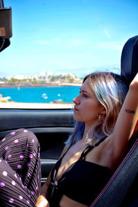Side view of young woman looking away while sitting in convertible