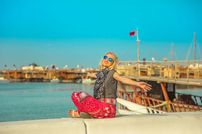 Portrait of woman wearing sunglasses at beach against clear sky