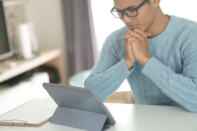 Midsection of man using mobile phone on table