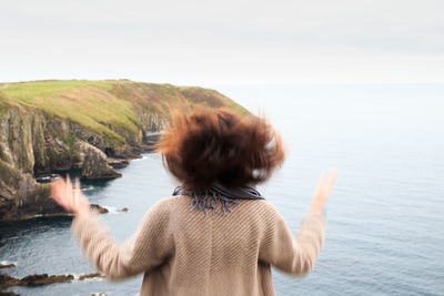 Rear view of woman standing at beach against clear sky