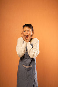 Portrait of young woman standing against yellow background