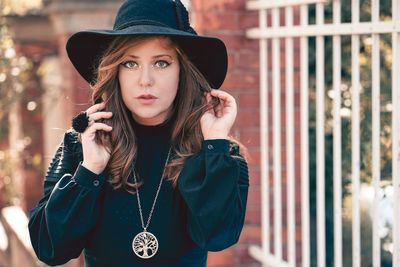 Portrait of young woman wearing hat standing outdoors