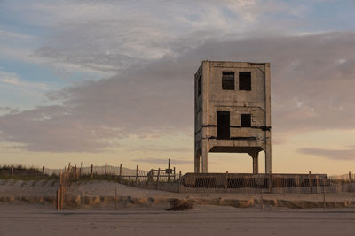 Abandoned building at beach against sky during sunset