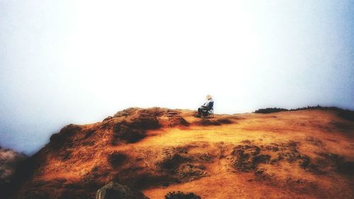 Person standing on rock against sky