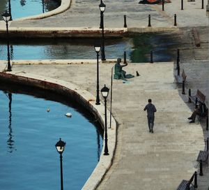 Rear view of woman walking on canal in city