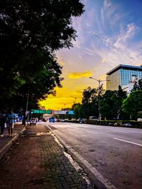 Road in city against sky at sunset