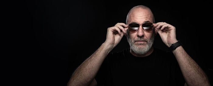 Portrait of woman wearing sunglasses against black background