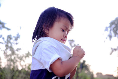 Side view of cute baby girl against sky