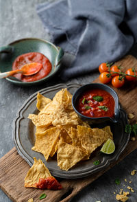 Traditional mexican appetizers of hot crispy nachos with tomato salsa sauce dip.