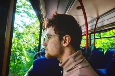 Side view of young man sitting in car