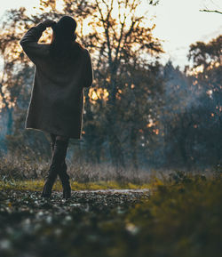 Rear view of woman standing by trees