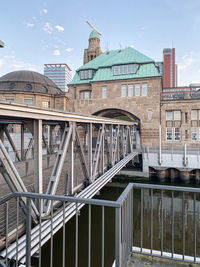 Bridge over canal by buildings against sky