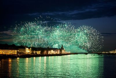 Firework display over river against sky at night