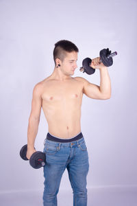 Full length of shirtless man standing against white background