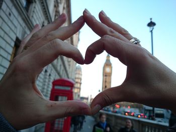 Cropped image of hands making heart shape with big ben in background