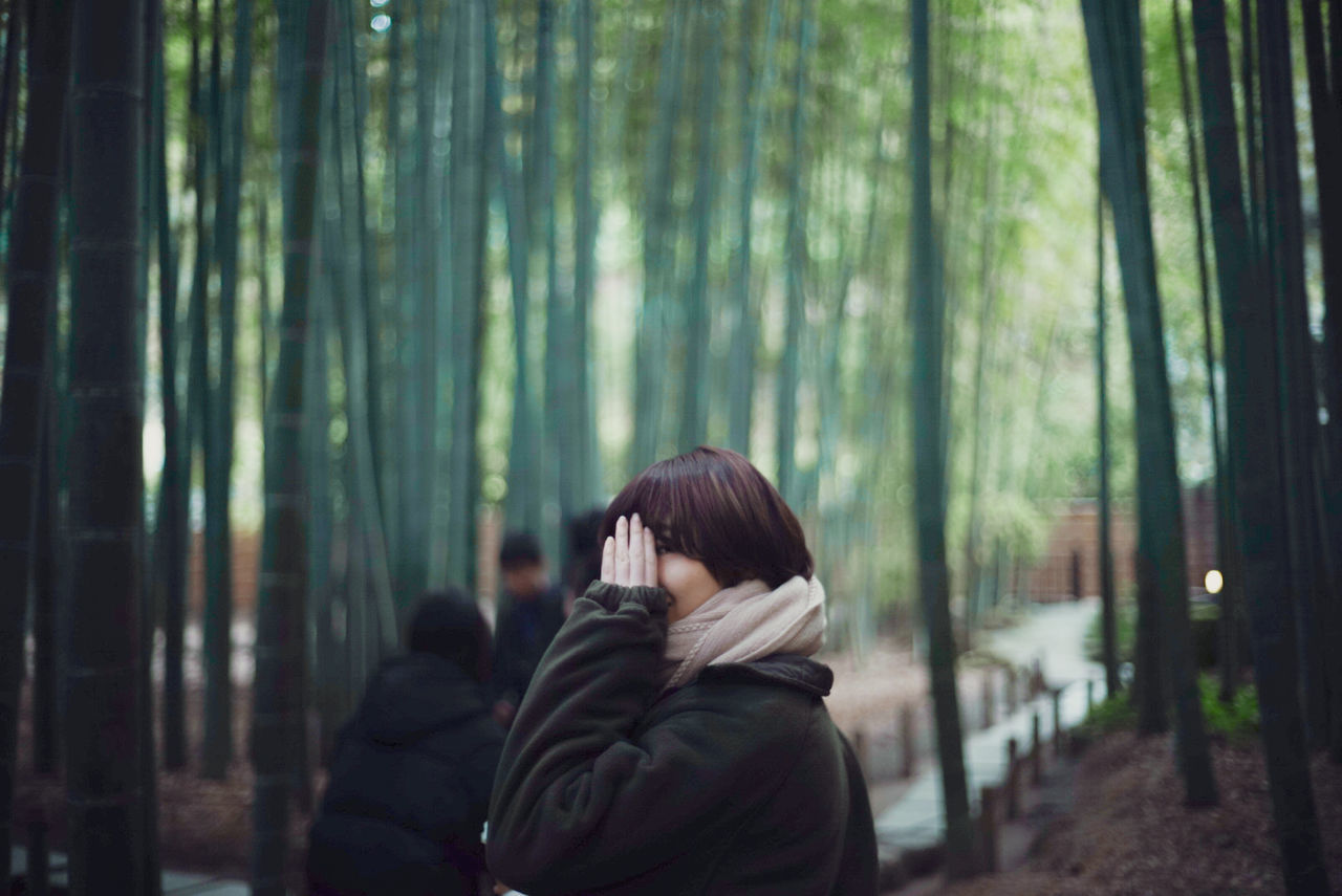 REAR VIEW OF WOMAN SITTING ON BAMBOO STRUCTURE