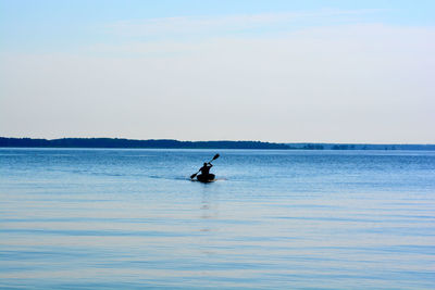 Silhouette man surfing in sea against sky