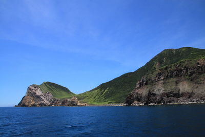 Scenic view of sea and mountains against clear blue sky