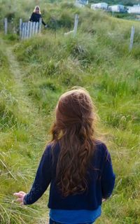 Rear view of girl walking on grassy field