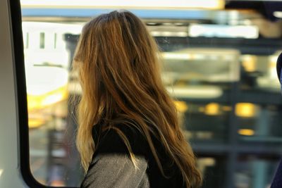 Rear view of woman looking through window