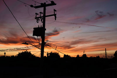 Low angle view of silhouette electricity pylon against sky during sunset