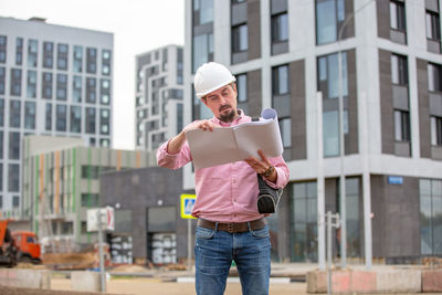 Full length of young man standing against buildings in city