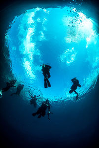 Low angle view of scuba divers swimming in sea