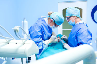 Doctors performing dental implantation in operating room