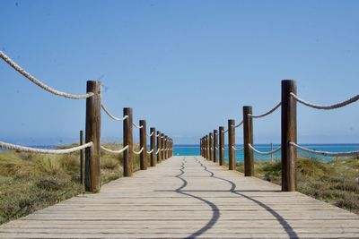 Pier over sea against clear blue sky