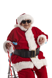 A nonagenarian in a santa claus costume sitting on a walker with a white background.