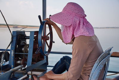 Portrait of cambodian man driving boat with pink hat