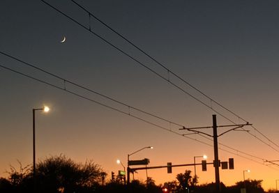 Low angle view of electricity pylon against sky at dusk