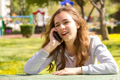 Portrait of young woman using phone while sitting on table