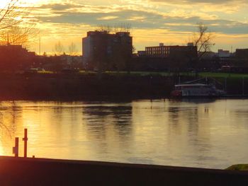 River by buildings against sky during sunset