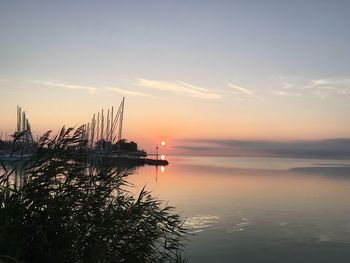 Scenic view of sea with harbor against sky during sunset