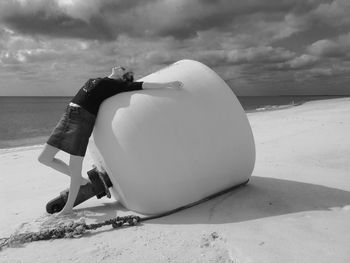 Full length of woman standing by buoy at beach