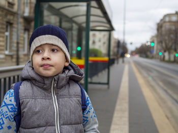 Young boy waiting bus for going to school. cold early morning time