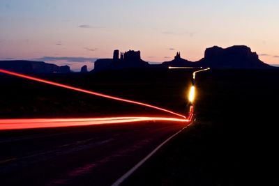 Light trails on road against sky at night