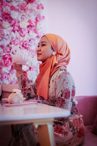 Woman with pink flower on table