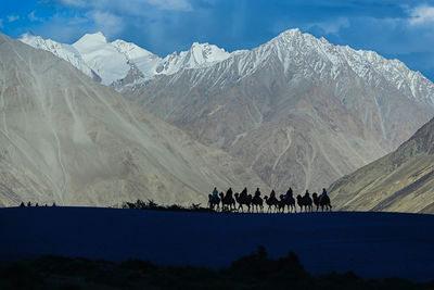 People walking on snow covered mountain range