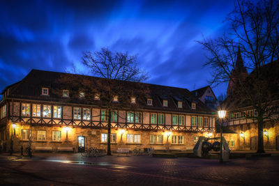 Illuminated building by street against sky at night